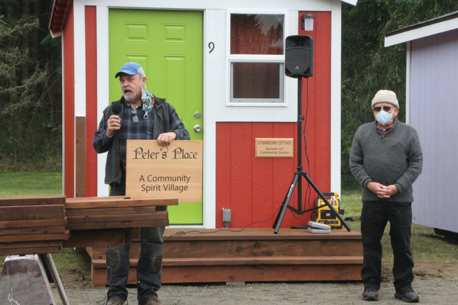 Randy Welle presents Peter Bonyun with a placard honoring his work to construct the 'Peter's Place' tiny home village in Port Hadlock.